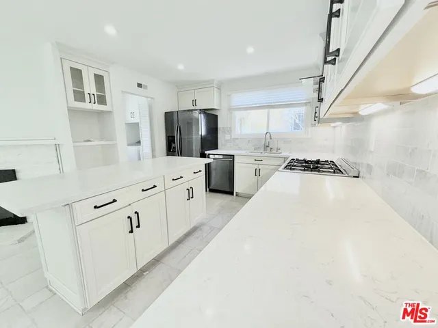 a kitchen with stainless steel appliances a refrigerator sink and white cabinets