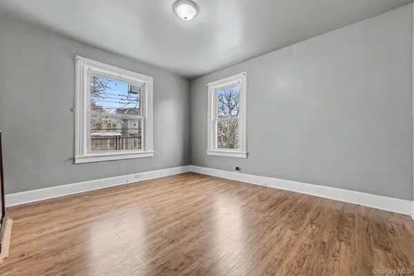 a view of an empty room with window and wooden floor