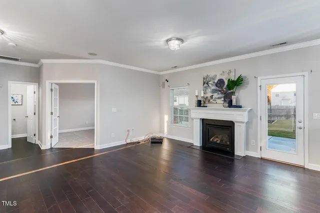 an empty room with wooden floor fireplace and windows