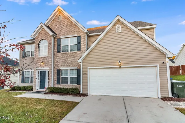 a view of a white house next to a yard and large tree