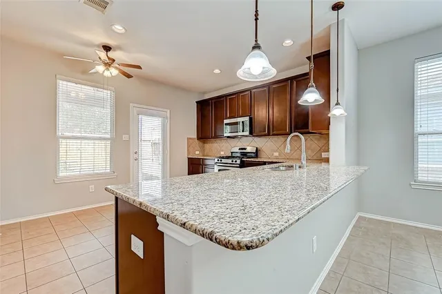 a kitchen with kitchen island granite countertop a stove center island a window and a refrigerator