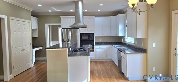 a kitchen with stainless steel appliances granite countertop a refrigerator a oven and a stove with wooden floor