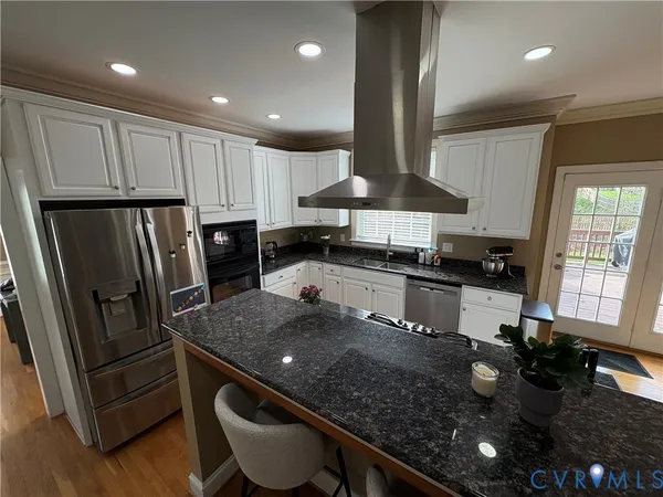 a kitchen with kitchen island granite countertop a sink appliances and cabinets