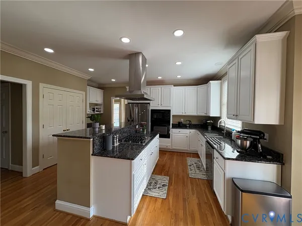 a kitchen with stainless steel appliances a refrigerator a stove top oven and wooden floor