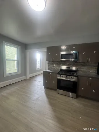 a large kitchen with stainless steel appliances granite countertop a stove a sink and a microwave