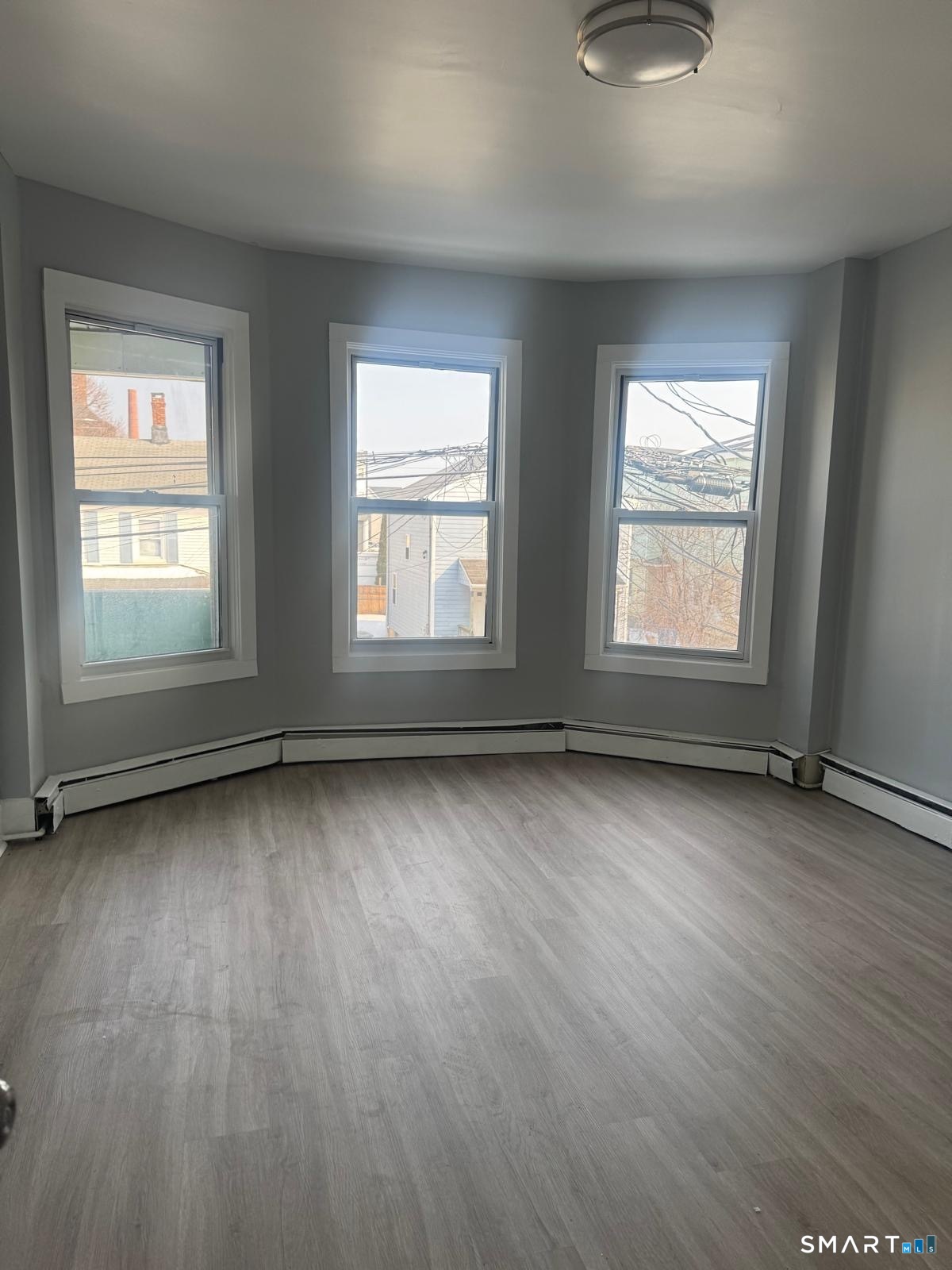 105 Caroline Street, Unit 3 Bridgeport, CT 06608 - Photo 5 of 7 an empty room with wooden floor and windows