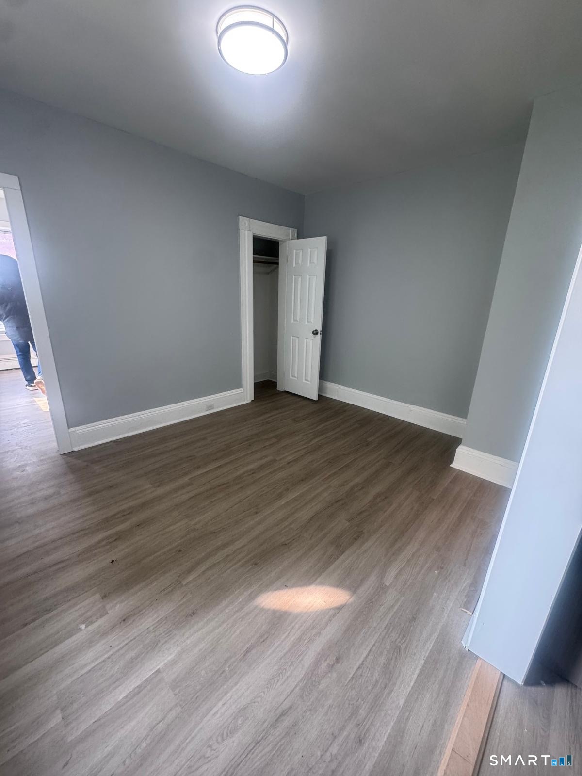 105 Caroline Street, Unit 3 Bridgeport, CT 06608 - Photo 7 of 7 an empty room with wooden floor and windows