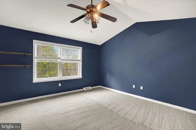 an empty room with a window and a ceiling fan