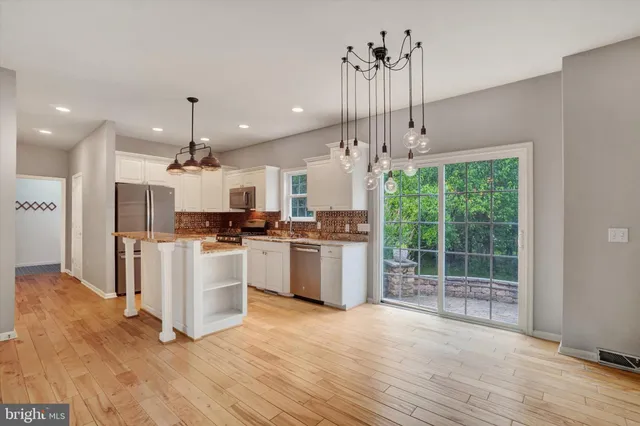 a large kitchen with kitchen island a stove a refrigerator a center island and a wooden floor