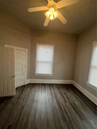 an empty room with wooden floor fan and windows