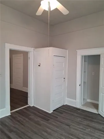 an empty room with wooden floor a ceiling fan and entryway