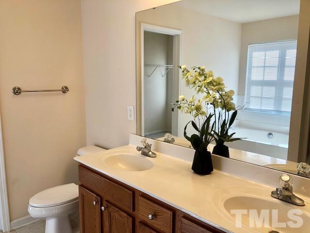 9810 Raleigh, NC 27617 - Photo 22 of 26 a bathroom with a sink a toilet and a mirror