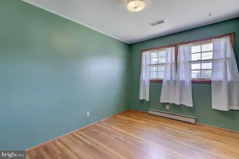 a view of hallway with window and wooden floor