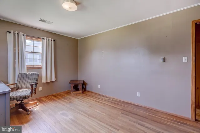an empty room with wooden floor closet and windows