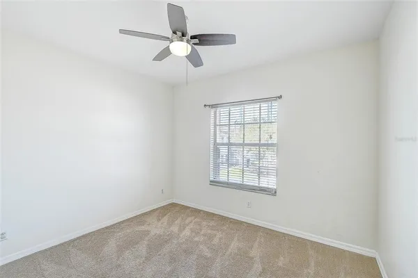 an empty room with a window and a fan