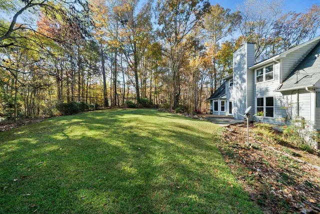 a view of a house with a big yard and large trees