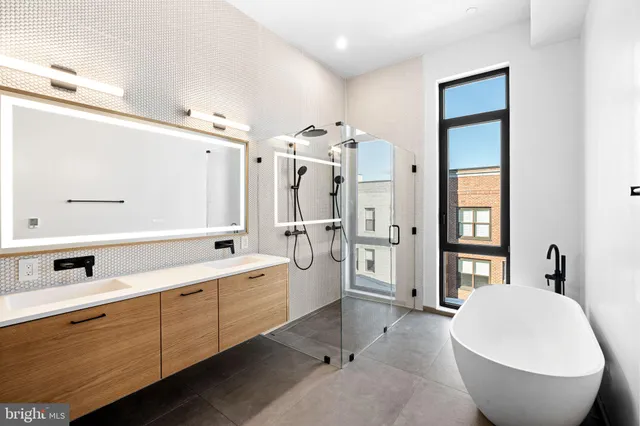 a spacious bathroom with a double vanity sink a mirror a bathtub and window