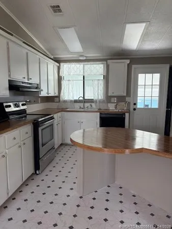 a kitchen with stainless steel appliances a sink a stove a refrigerator cabinets and a window