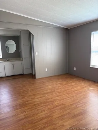 a view of an empty room with wooden floor and windows