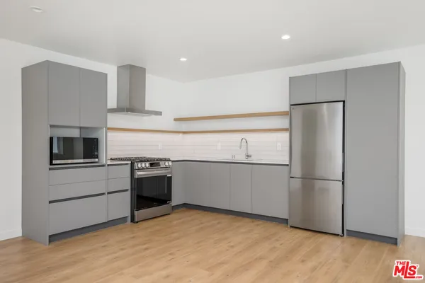 a kitchen with a refrigerator stove and wooden floor