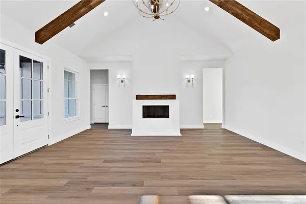a view of an empty room with wooden floor and a kitchen