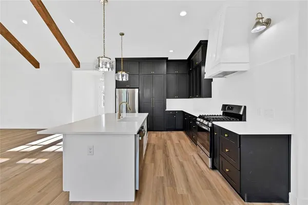 a kitchen with stainless steel appliances granite countertop a sink a stove and a refrigerator