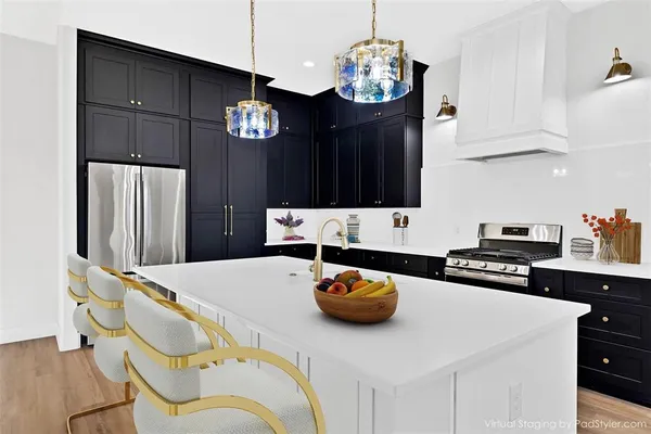 a kitchen with stainless steel appliances kitchen island granite countertop a refrigerator a stove a sink dishwasher and white cabinets with wooden floor