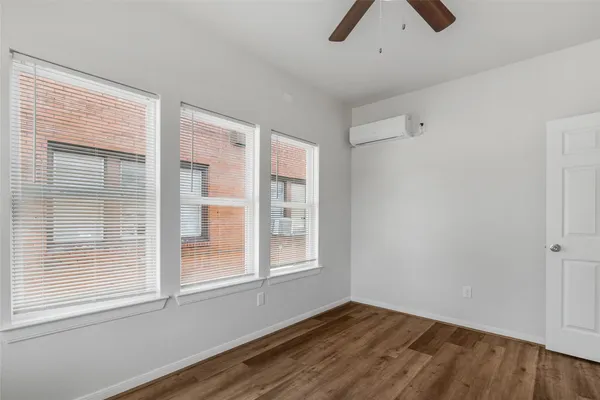 a view of empty room with wooden floor and fan
