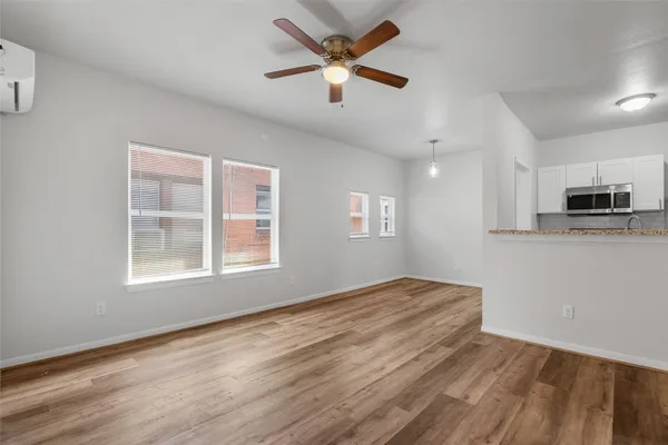 a view of an empty room with window and wooden floor