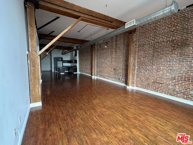 an empty room with wooden floor and a floor to ceiling window
