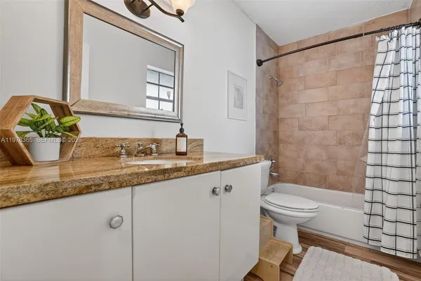 a bathroom with a granite countertop sink toilet and shower