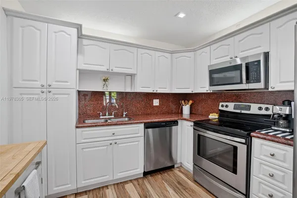 a kitchen with cabinets stainless steel appliances and wooden floor