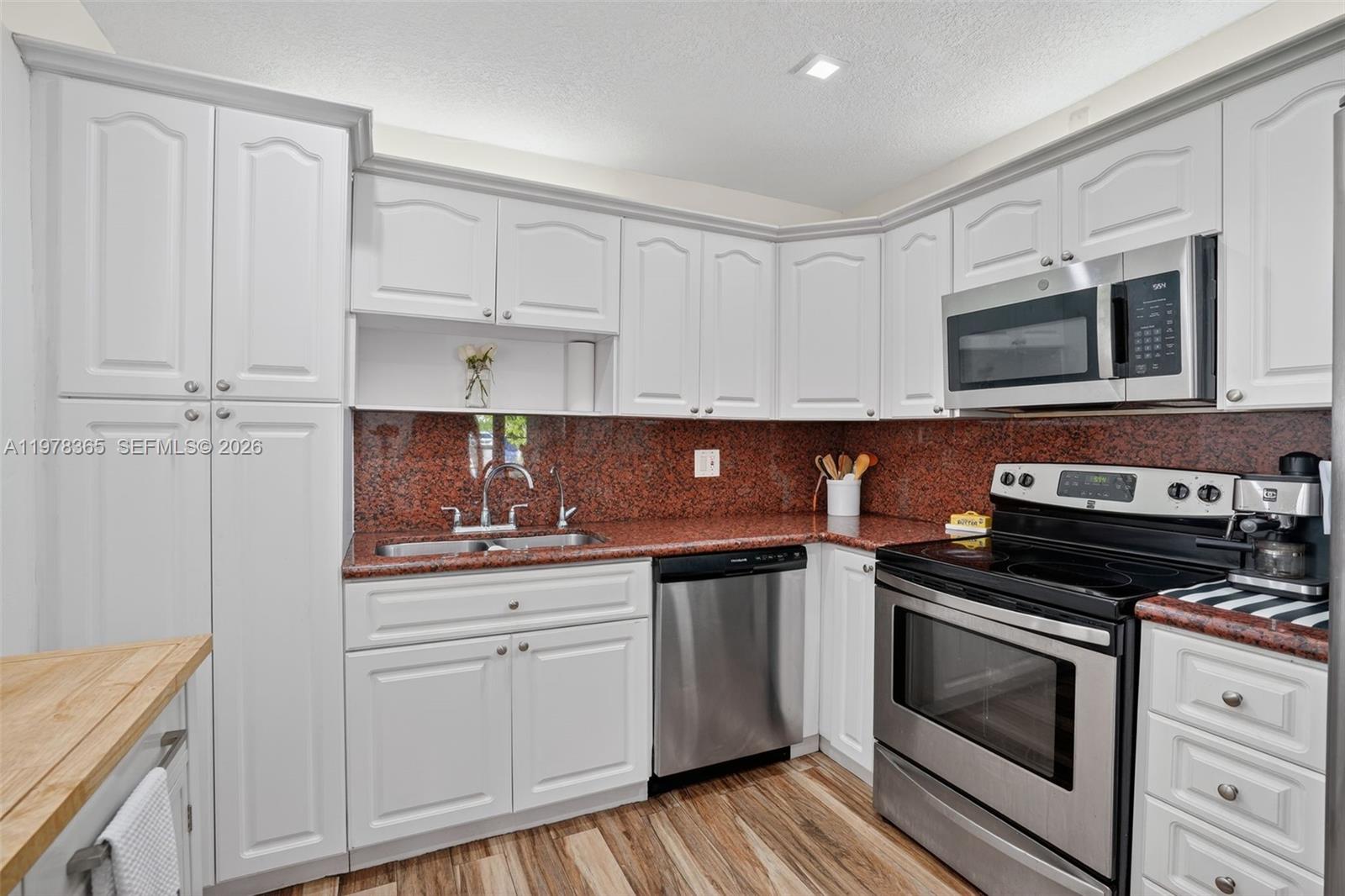 7016 Southwest 103rd Place Miami, FL 33173 - Photo 9 of 21 a kitchen with cabinets stainless steel appliances and wooden floor