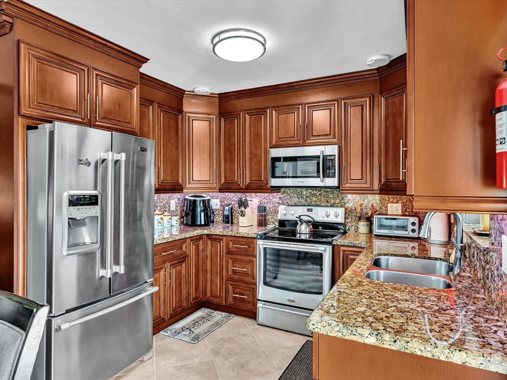 5180 Southwest 13th Street Plantation, FL 33317 - Photo 18 of 54 a kitchen with stainless steel appliances granite countertop a refrigerator stove top oven and sink