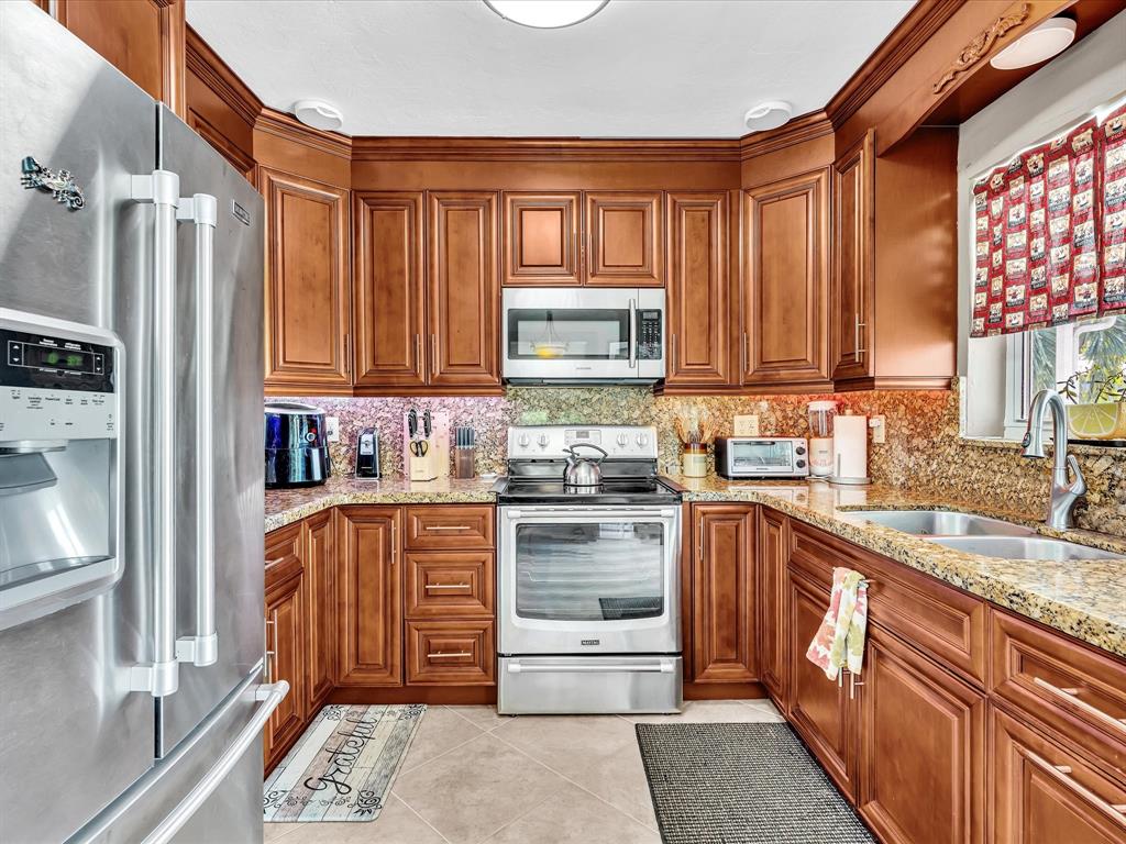 5180 Southwest 13th Street Plantation, FL 33317 - Photo 21 of 54 a kitchen with stainless steel appliances granite countertop a refrigerator stove and sink