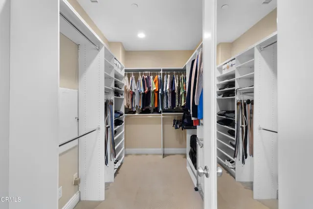 a view of walk in closet with clothes and shoes
