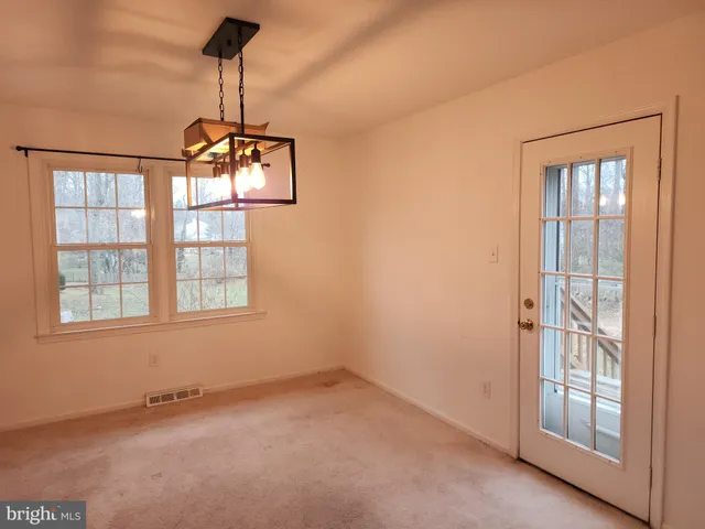 an empty room with windows and chandelier fan