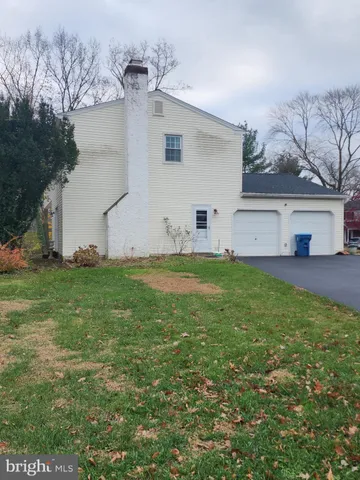 a view of a white house with a big yard and large trees
