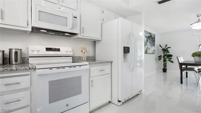 a kitchen with white cabinets and white appliances