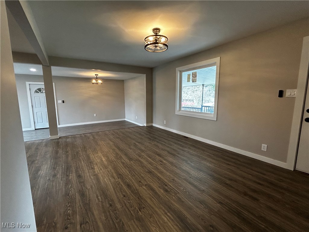 3465 Ridge Road Zanesville, OH 43701 - Photo 2 of 16 Unfurnished living room featuring dark wood finished floors, baseboards, and an inviting chandelier
