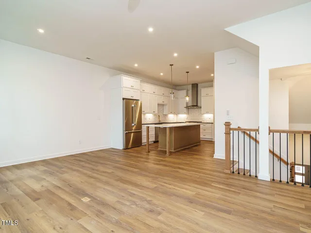 a large white kitchen with wooden floors and stainless steel appliances
