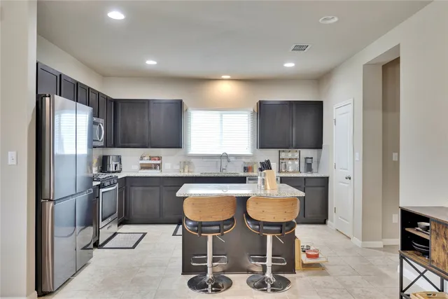 a kitchen with refrigerator and chairs