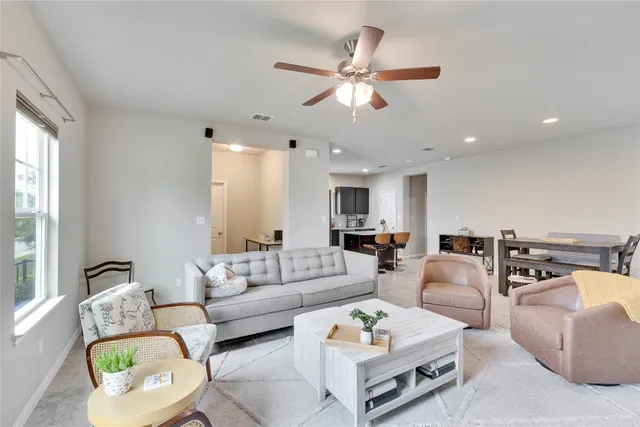 a living room with furniture kitchen view and a large window