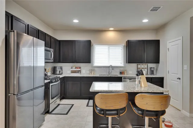 a kitchen with stainless steel appliances granite countertop a sink refrigerator and microwave