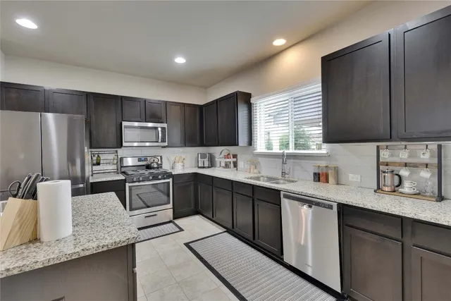 a kitchen with stainless steel appliances granite countertop sink stove refrigerator and cabinets