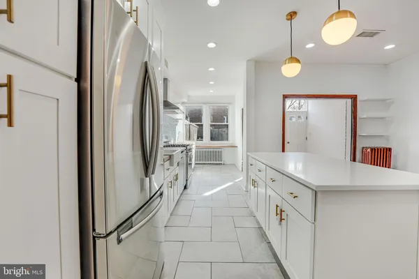 a kitchen with stainless steel appliances granite countertop a stove a sink and white cabinets with wooden floor