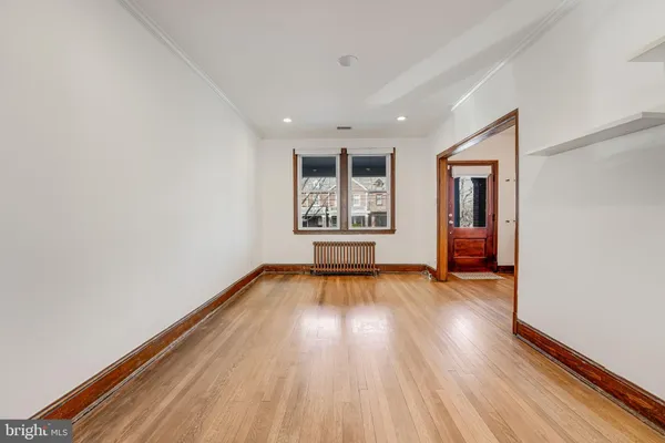 a view of a hallway with wooden floor and a bathroom