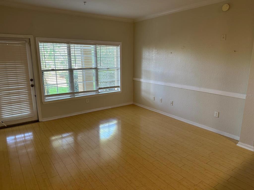 3757 Conroy Road, Unit 2512 Orlando, FL 32839 - Photo 5 of 13 an empty room with wooden floor and windows with curtains