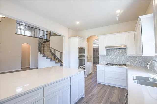 a large kitchen with kitchen island a sink dishwasher a stove and a refrigerator with wooden floor