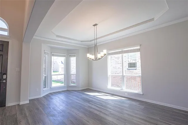 a view of an empty room with wooden floor and windows